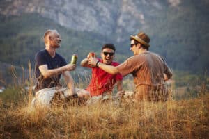 Three friends enjoying a can of beer outdoors
